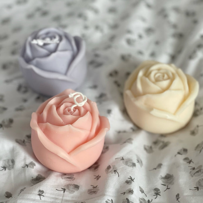 three rose candles on a floral sheet
